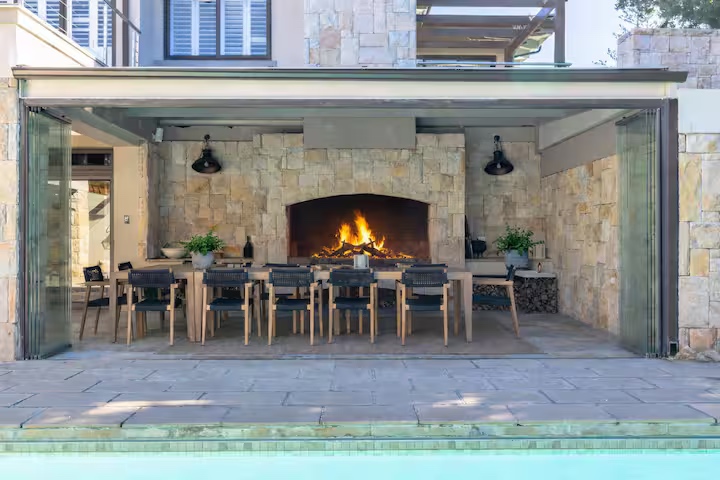 Outdoor fireplace dining area beside the pool